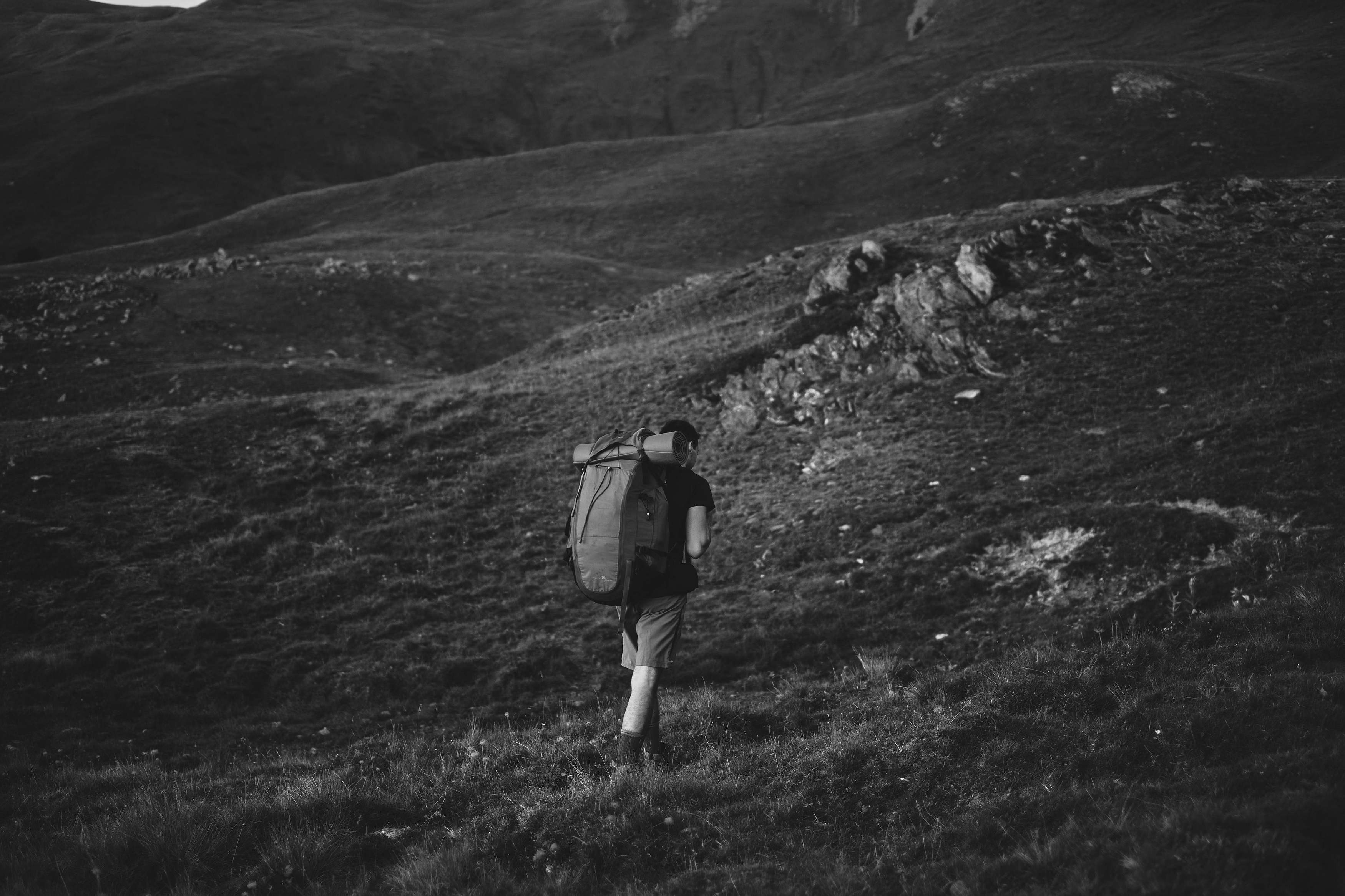 black and white photo man hiking on hillside